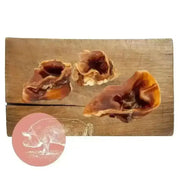 Pork Crunch natural dog chew: pig ear treat with brown skin and white fat on wooden board