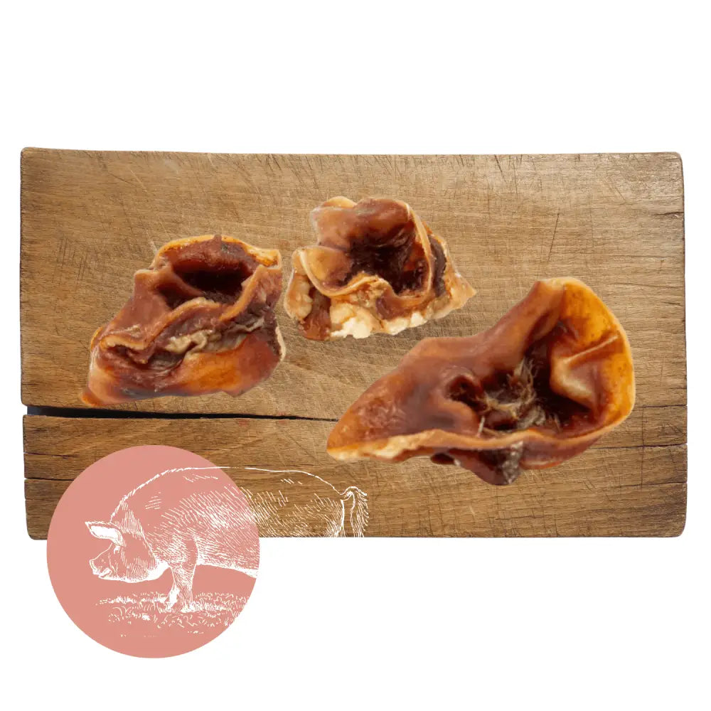 Pork Crunch natural dog treat: pig ear with brown skin and white fat on wooden board