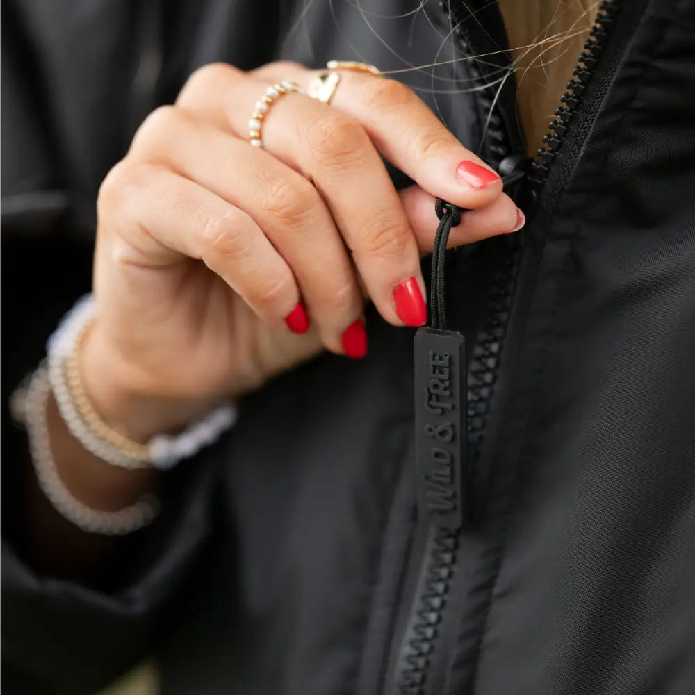 Black zipper pull with white logo on The Cobe changing robe in black
