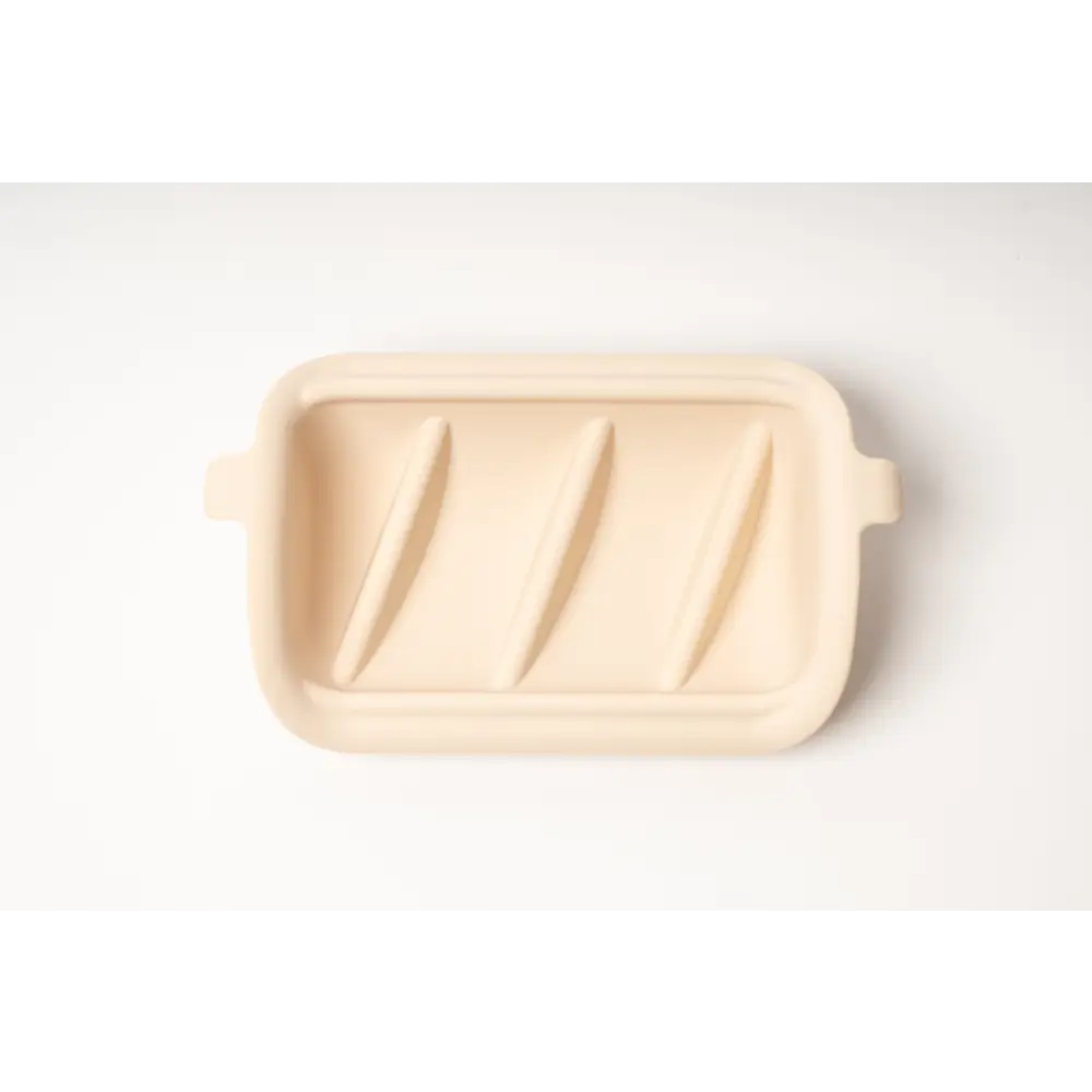 Cream-colored ceramic slow feeder insert with grooves and handles