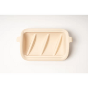 Cream-colored ceramic slow feeder insert with grooves and handles
