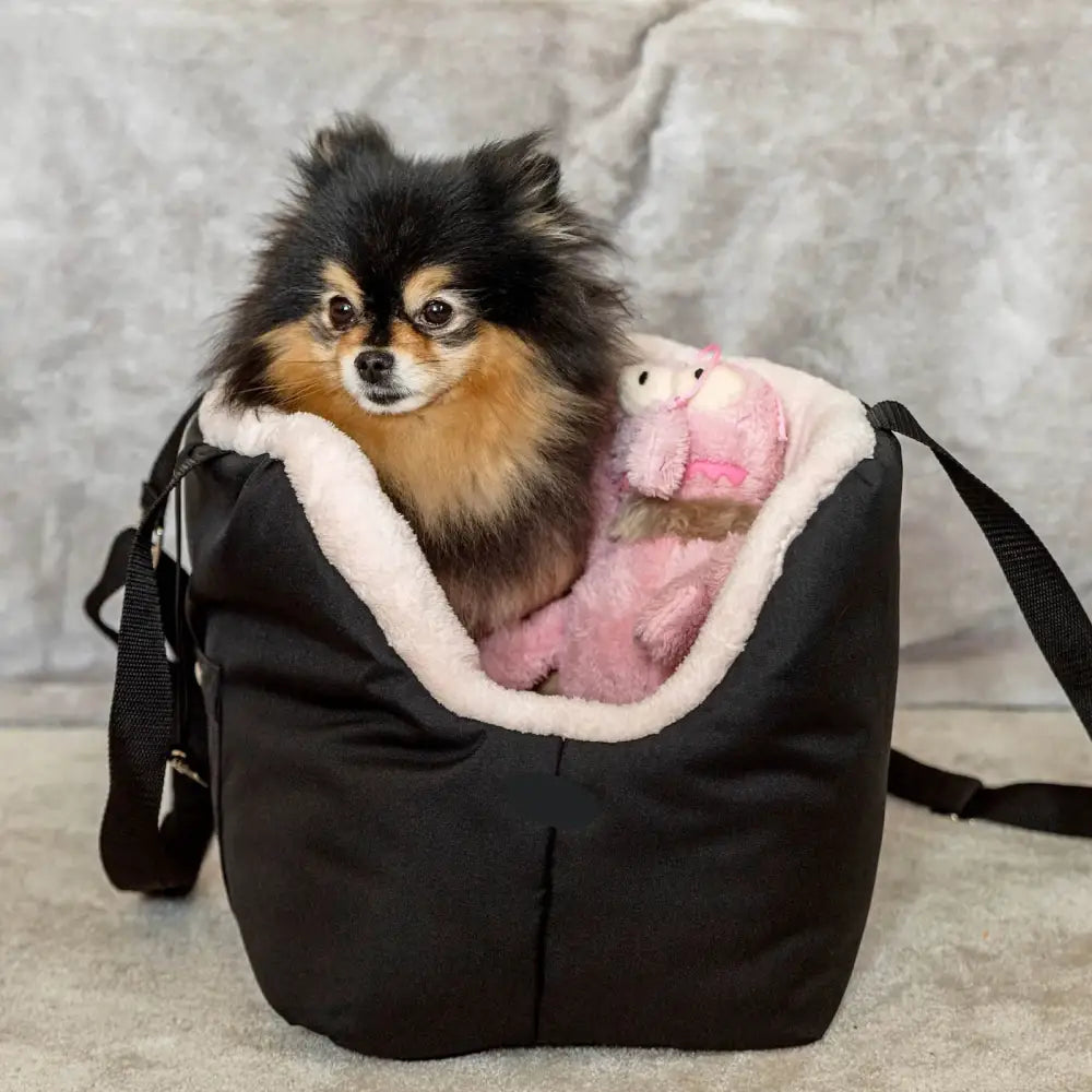 Black Soho Poms pet carrier with plush lining and pink stuffed animal toy inside