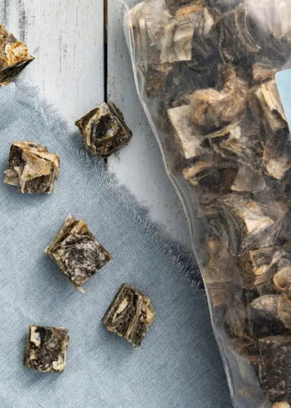 Square-shaped, dark brown and beige dried fish treats with a textured surface.