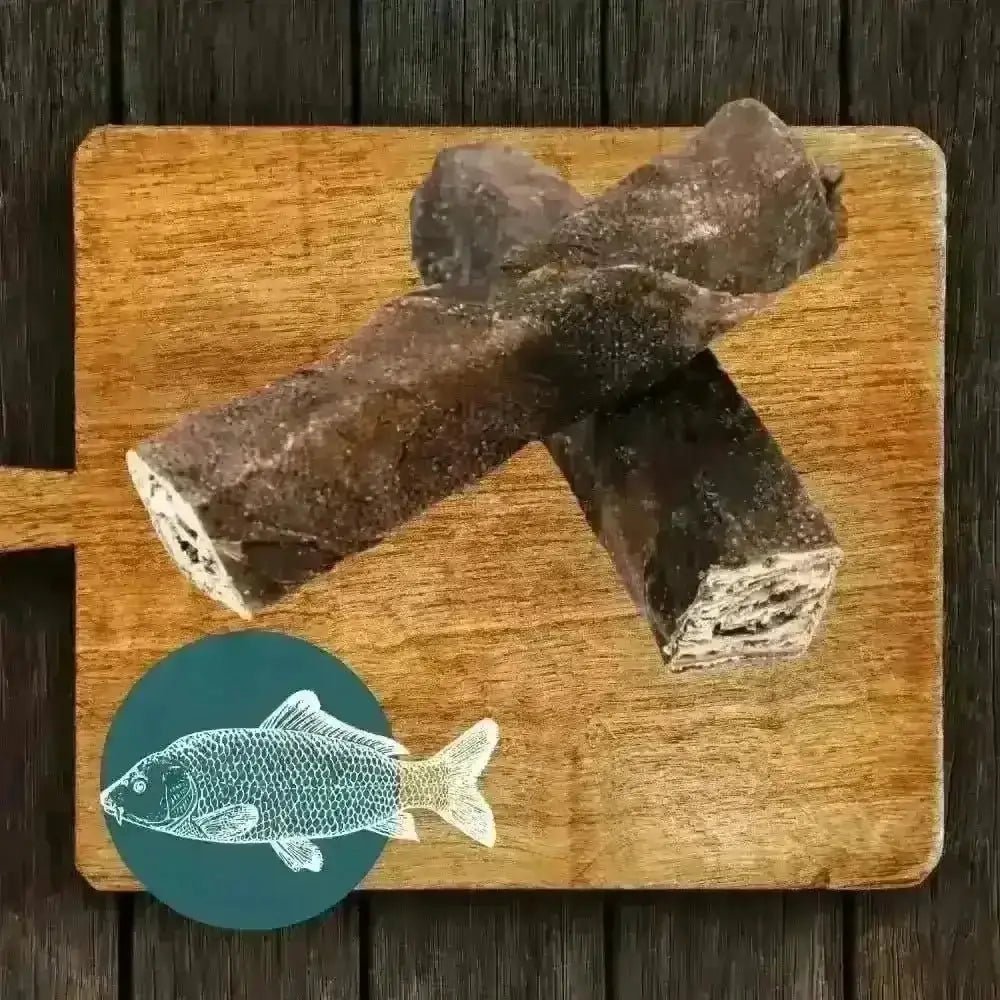 Brown fish-shaped dog treat on wooden board with teal fish icon for The Fish Chew Box wolf fish stick