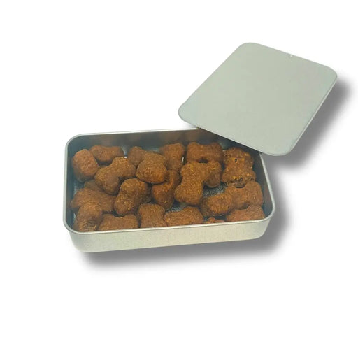 Metal tin filled with cat and dog treats shaped like bones on a white background