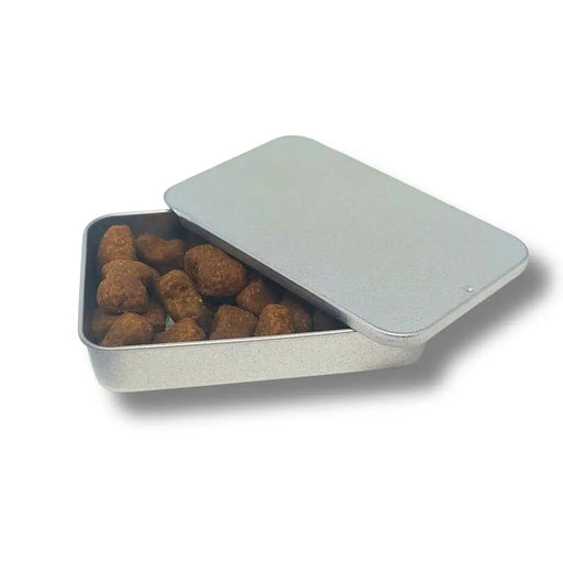 Metal tin with a lid containing brown dog treats on a white background