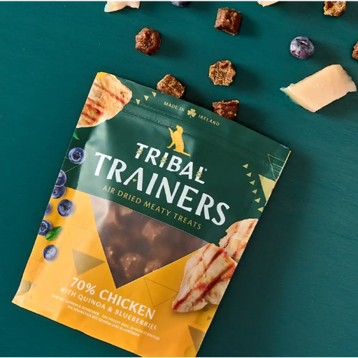 Tribal Trainers dog treat package on a teal background with treats around it.