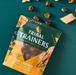 Tribal Trainers dog treat package on a teal background with treats around it.