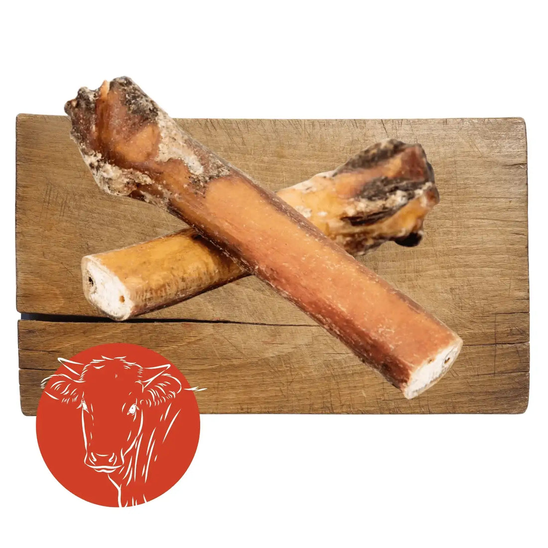 Two natural, unprocessed beef bones with a light brown exterior and white interior, resting on a wooden cutting board.