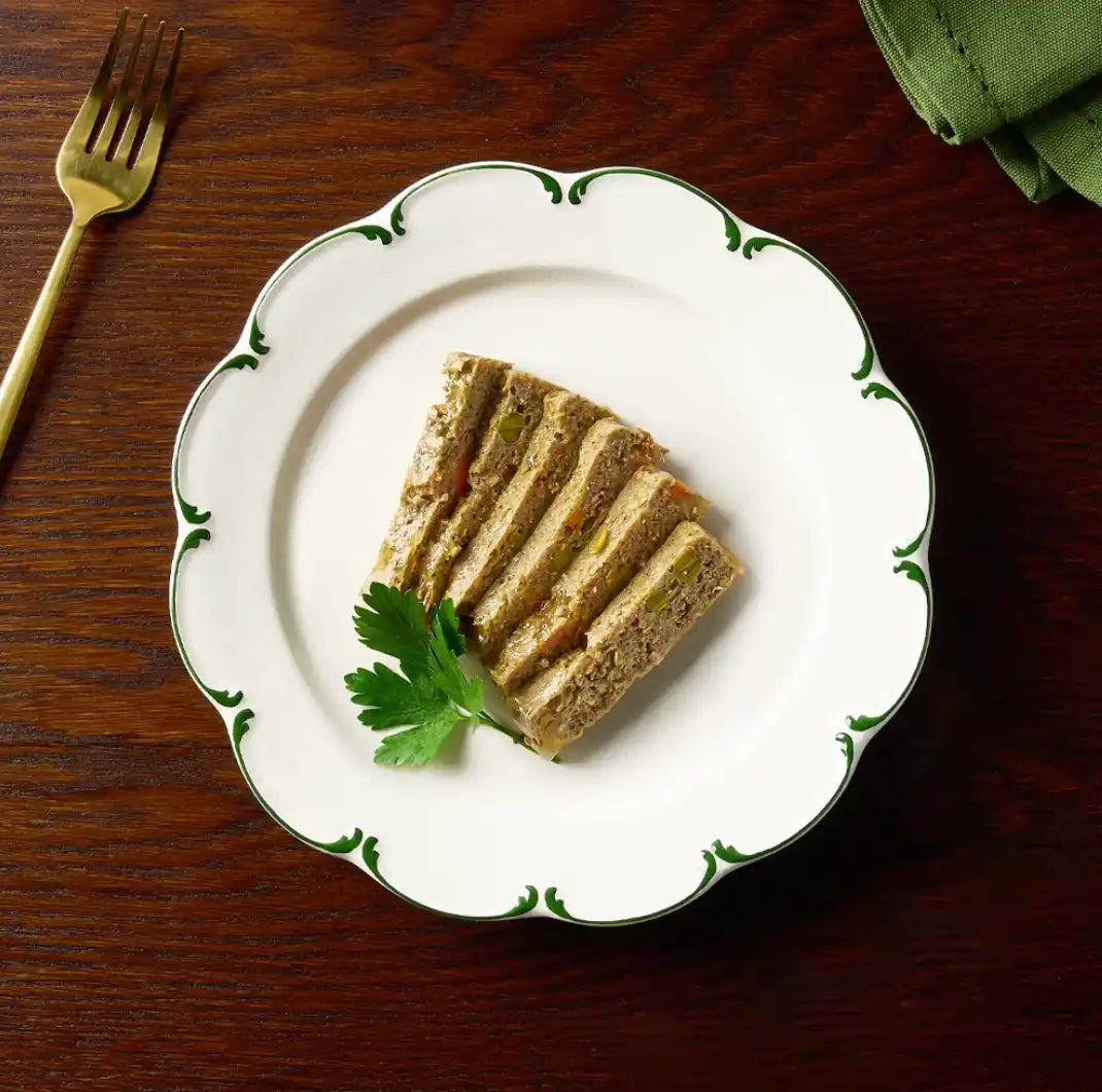 White scalloped plate with green leaf design, gold fork and napkin.